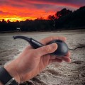 smoking tobacco in a wood pipe at sunset